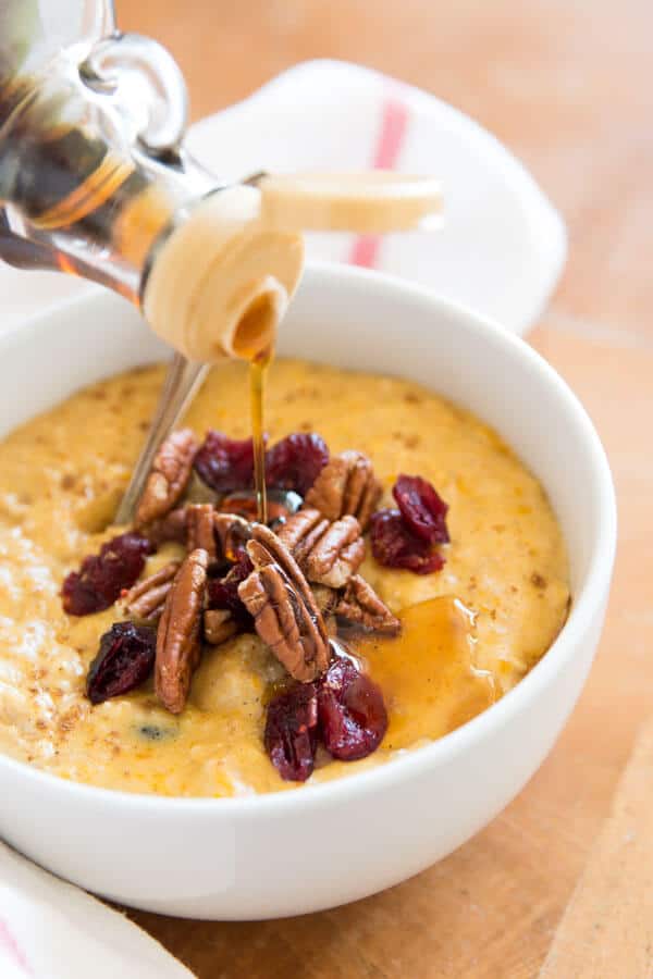 pouring maple syrup over bowl of pumpkin oatmeal