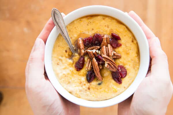 top down view of female hands holding bowl of pumpkin oatmeal