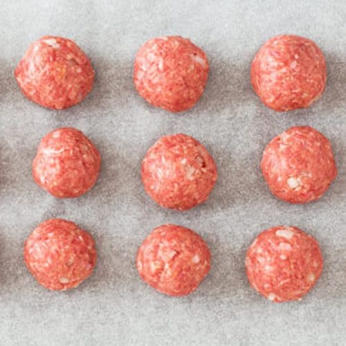 nine raw meatballs on parchment