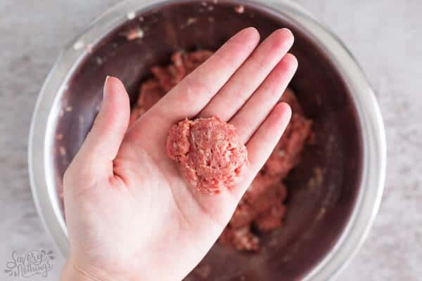 female hand with ground beef for meatballs in palm