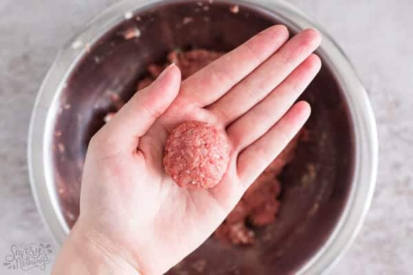 female hand holding shaped meatball