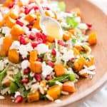 female hand holding a spoon to drizzle dressing over a wild rice salad