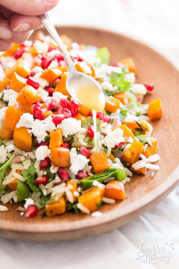 spooning dressing over wild rice salad