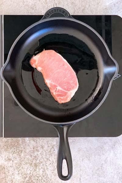Raw pork chop in a cast iron skillet