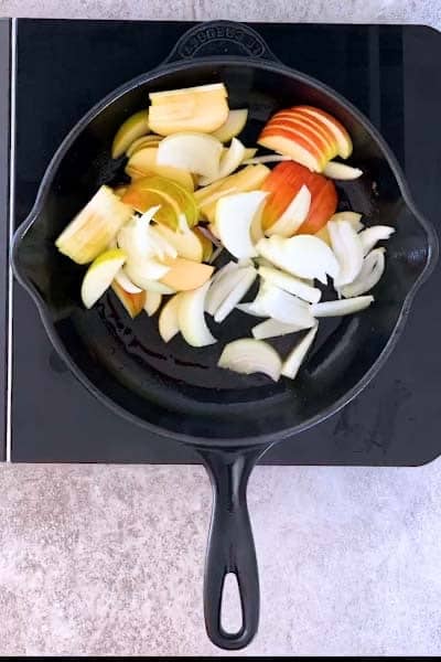 raw apples and onions in a cast iron skillet