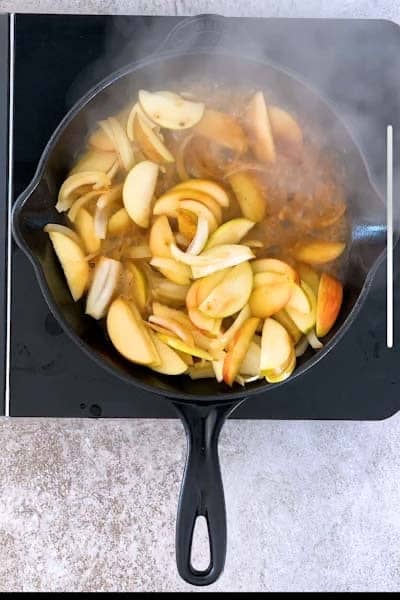 deglazing a cast iron skillet filled with apples and onions