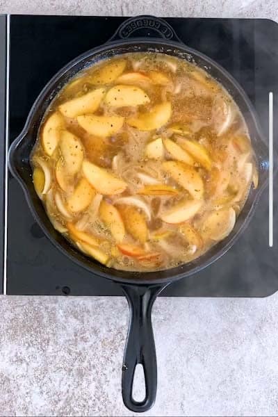 Cast iron skillet filled with apples, onions and gravy