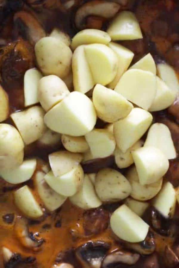 raw potatoes in a skillet with beef and vegetables