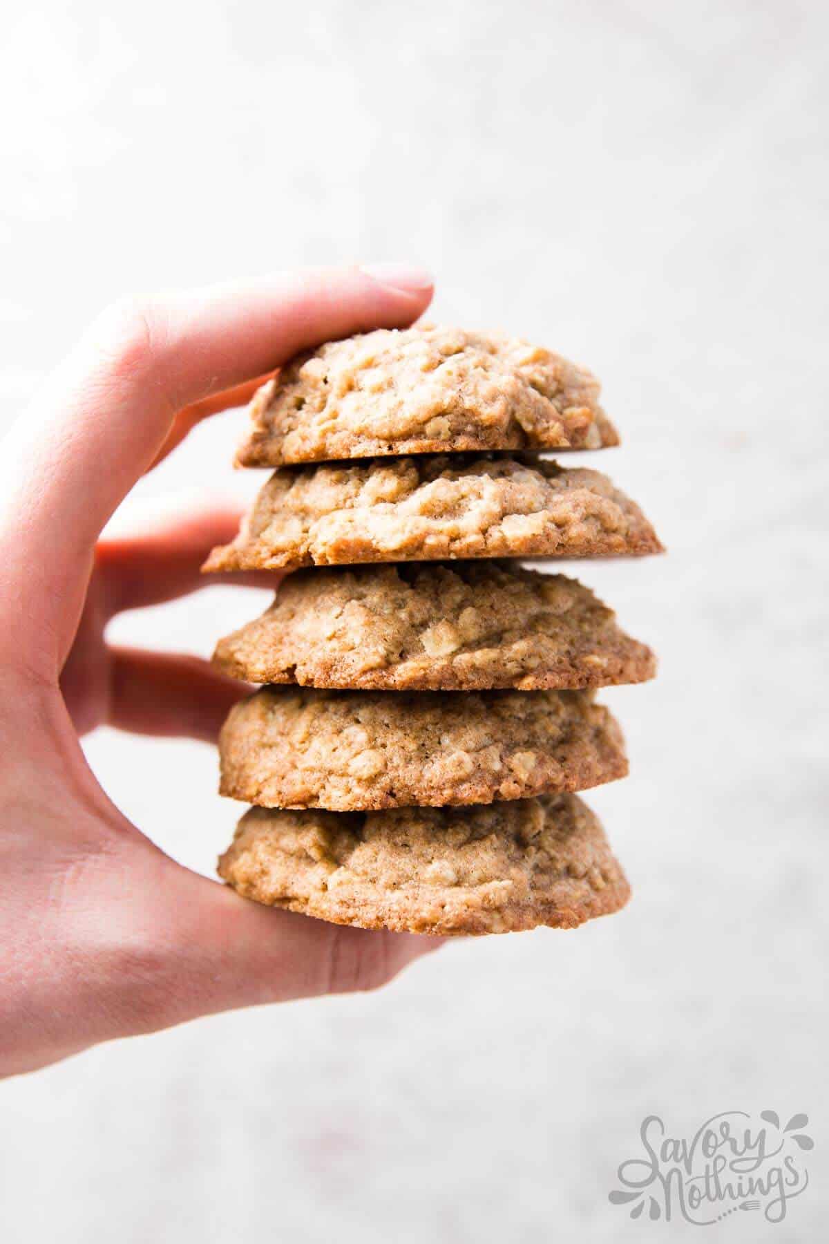 female hand holding a stack of homemade oatmeal cookies