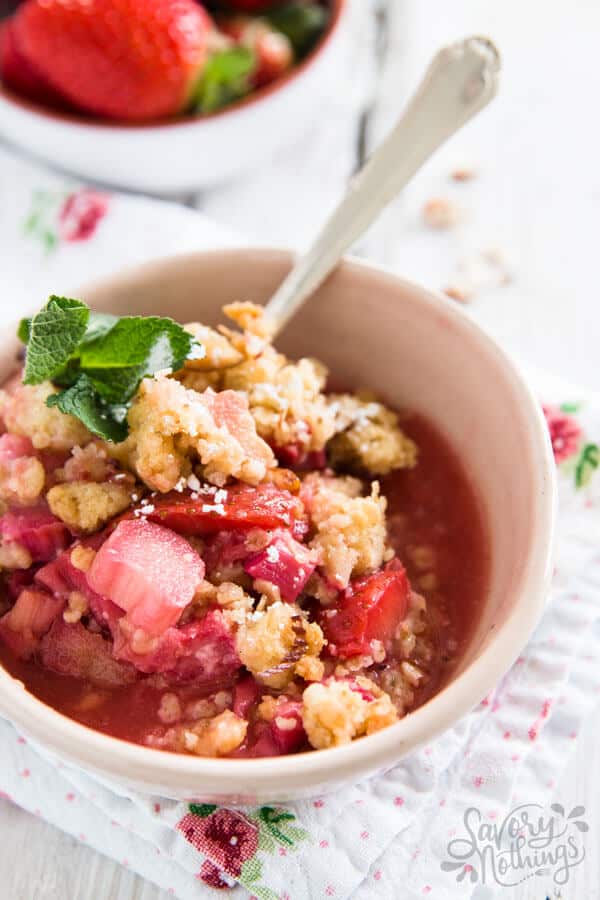 angled view on strawberry rhubarb crisp in light pink bowl