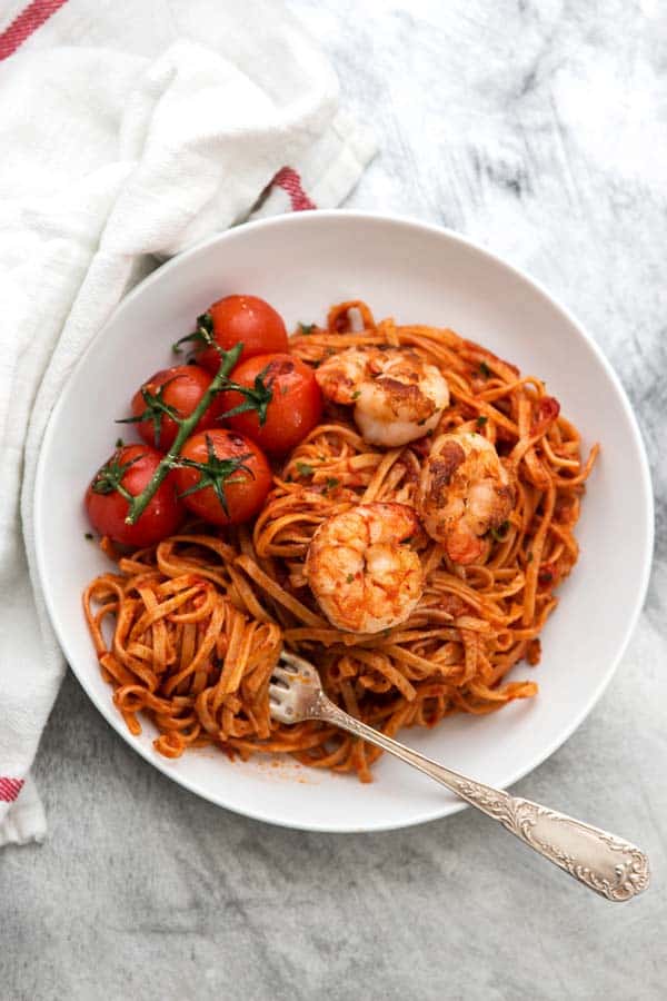 overhead photo of white plate with garlic butter tomato shrimp pasta