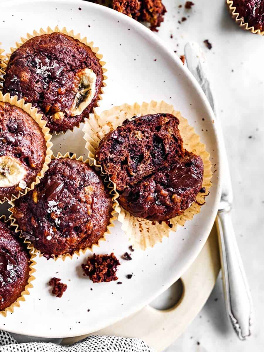 close up photo of halved chocolate banana muffin on plate