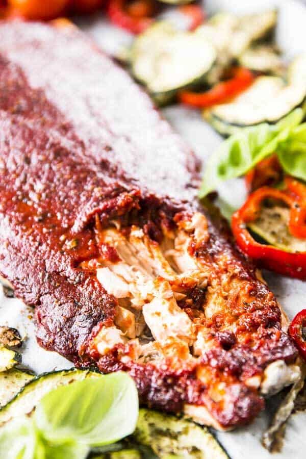 close up photo of flaked salmon surrounded by roasted vegetables and fresh basil