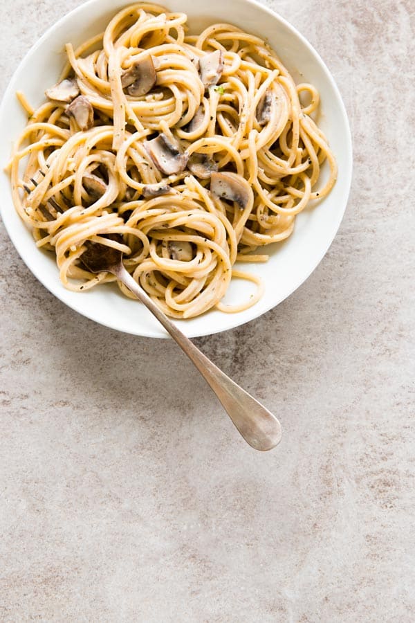 top down view on mushroom pasta in white bowl with fork