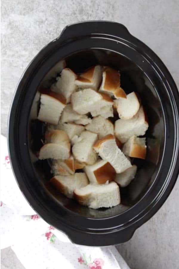black crock from a slow cooker filled with cubed challah bread