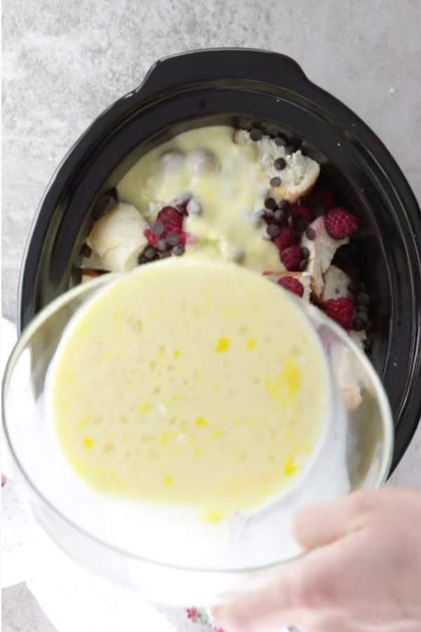 pouring custard over ingredients for crock pot French toast