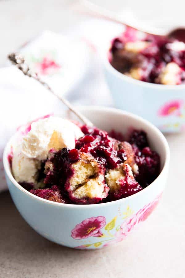 two colourful bowls with berry cobbler and ice cream