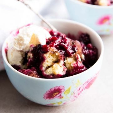 close up of berry cobbler in colourful bowl with ice cream