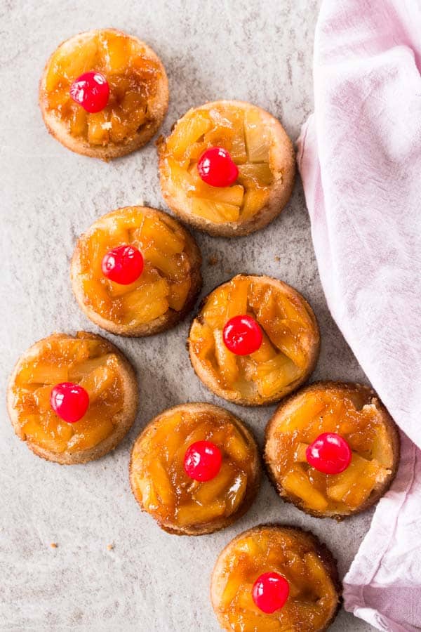 8 pineapple upside down cupcakes on the counter with a pink cloth