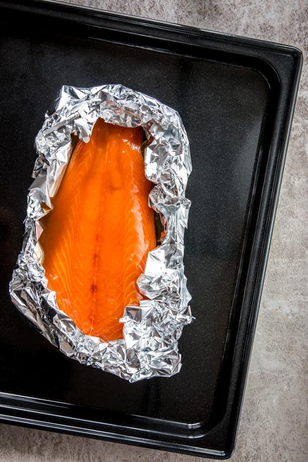 raw salmon with teriyaki sauce in foil on sheet pan