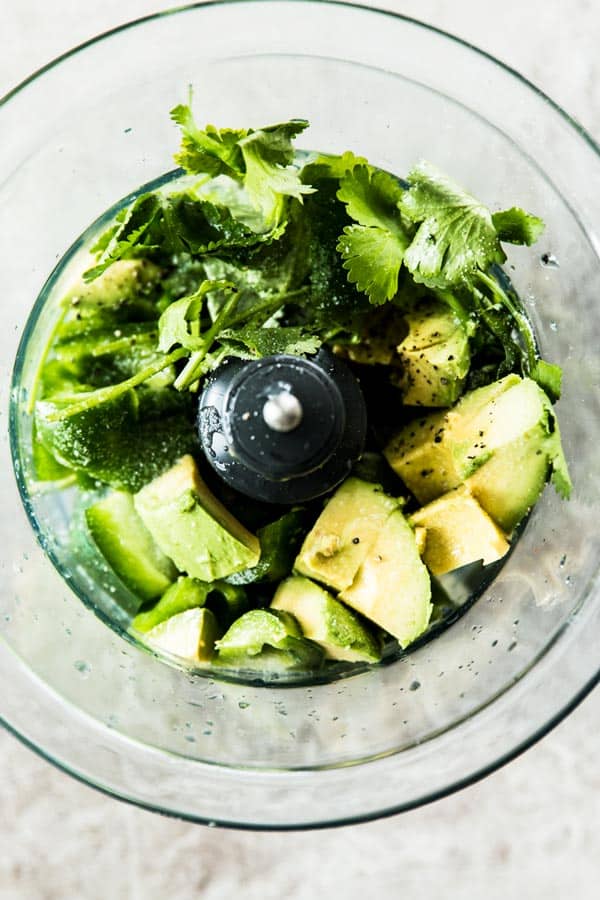top down view on food processor bowl with ingredient for avocado dipping sauce