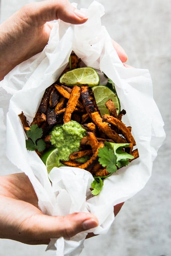 overhead view on female hands holding sweet potato fries wrapped in baking parchment