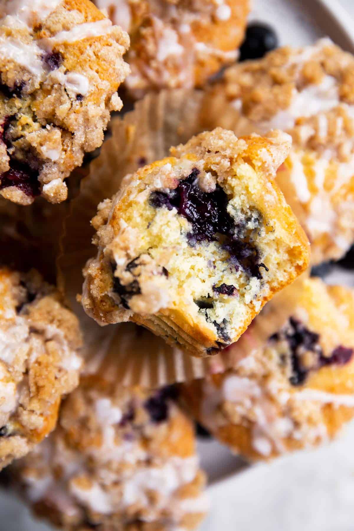 overhead view of blueberry muffin with bite taken out on plate with more muffins