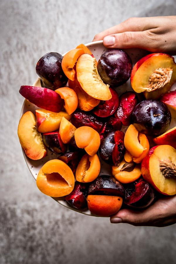 Sliced stone fruit held on a pottery plate.