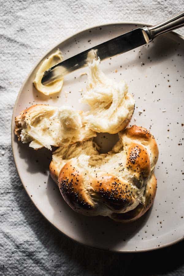 Fluffy Challah bread rolls, aka Swiss Zopf on a plate with butter.