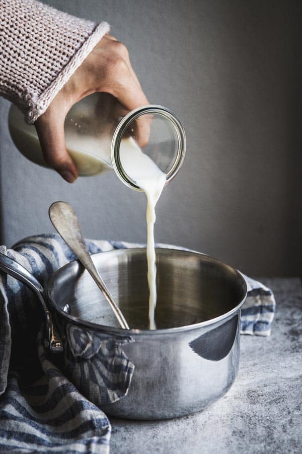 Pouring milk into a small saucepan.