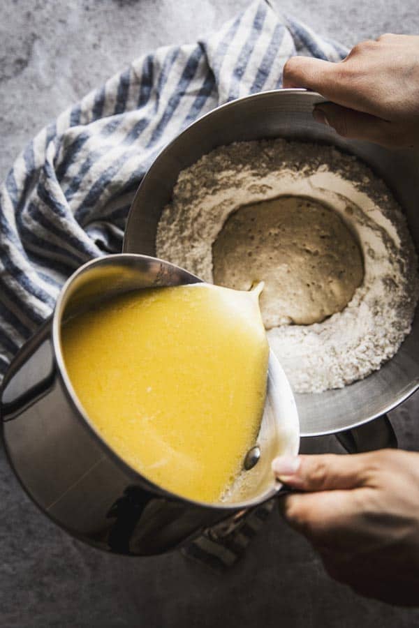 Pouring milk and melted butter into challah bread dough.