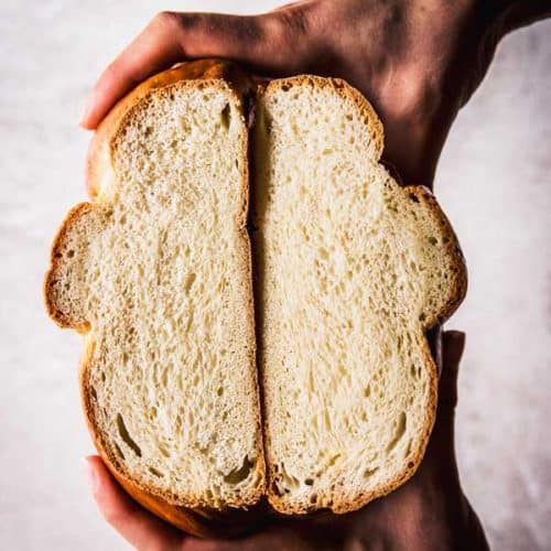 top down view on female hands holding sliced open braided bread