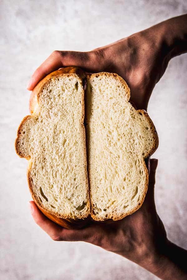 top down view on female hands holding sliced open braided bread