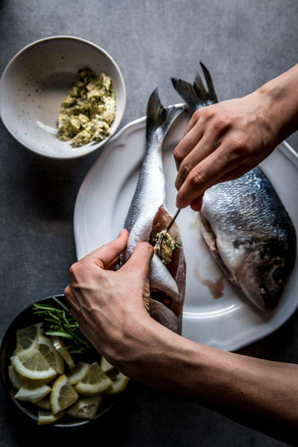 Stuffing baked whole fish with garlic herb compound butter.