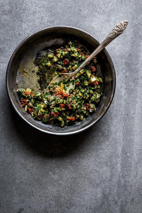 overhead view on black dish with briny caper and sun dried tomato salsa