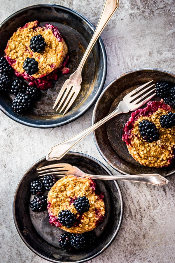overhead view on three dark dishes with blackberry baked oatmeal