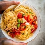 female hands holding plate with caprese pasta