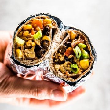 female hand holding breakfast burrito cut in half