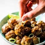 female hand sticking toothpick into meatball