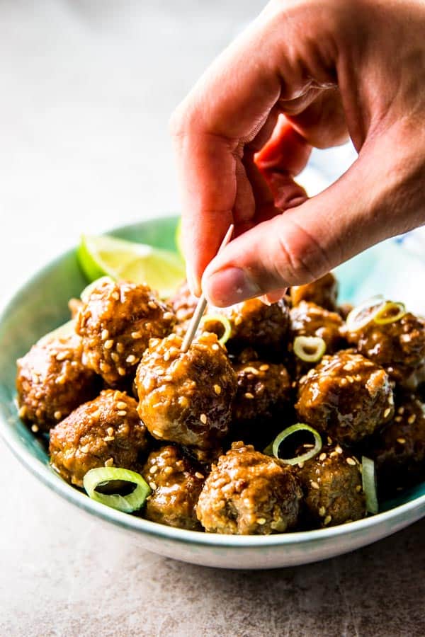 female hand sticking toothpick into meatball