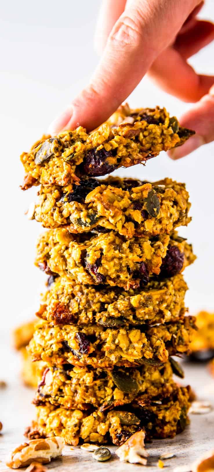 female hand grabbing top cookie from stack of pumpkin breakfast cookies