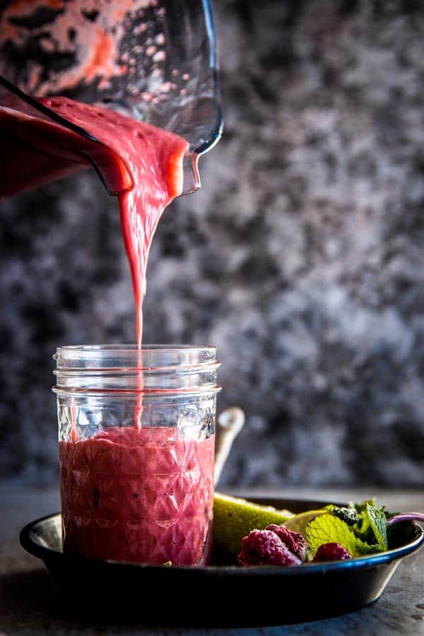 Pouring raspberry mango smoothie into a glass.