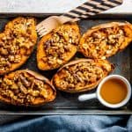 rimmed baking sheet with sweet potato skins and a small bowl with maple syrup on the side