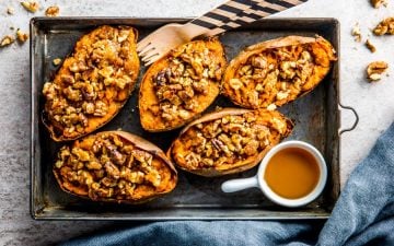 rimmed baking sheet with sweet potato skins and a small bowl with maple syrup on the side