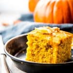 slice of pumpkin cornbread on metal dish in front of pumpkin