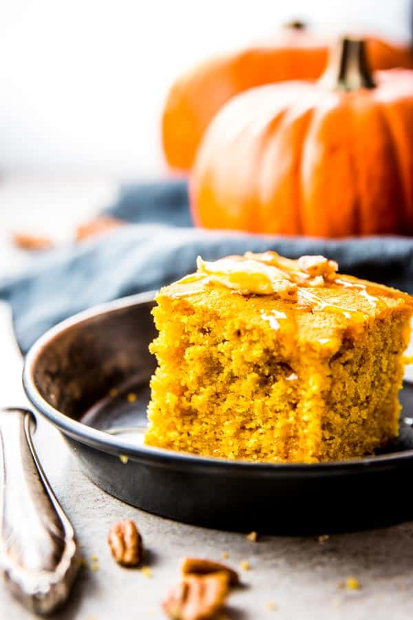 slice of pumpkin cornbread on metal dish in front of pumpkin