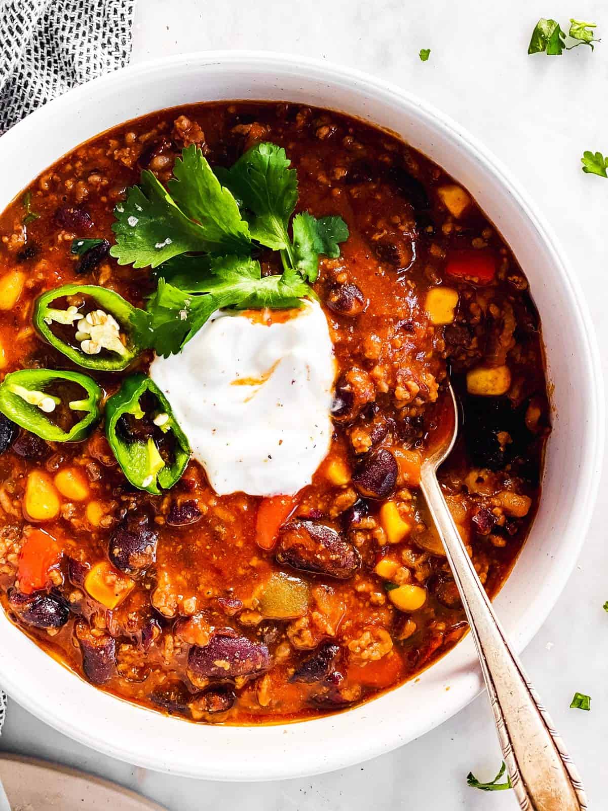 overhead view of white bowl with crockpot chili and toppings