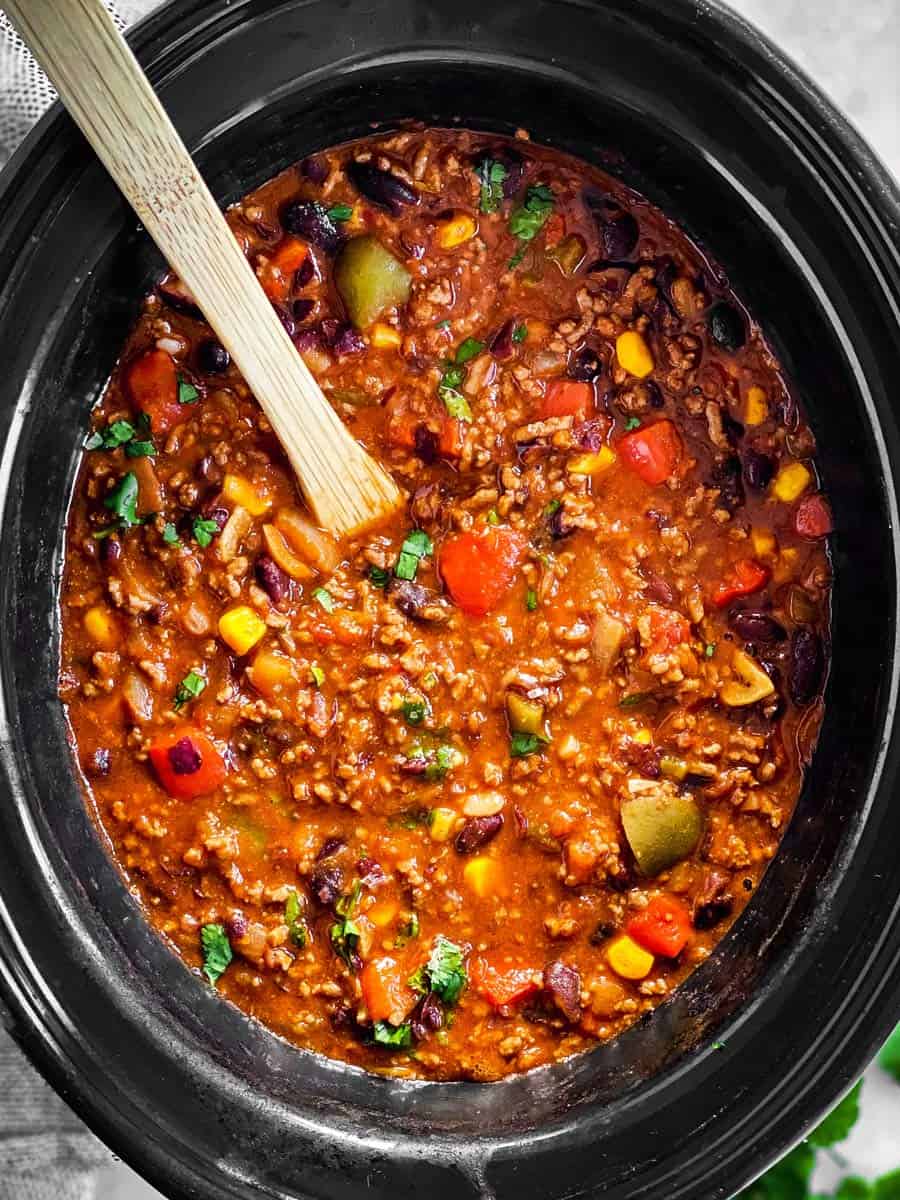 chili in black crock with wooden spoon inside