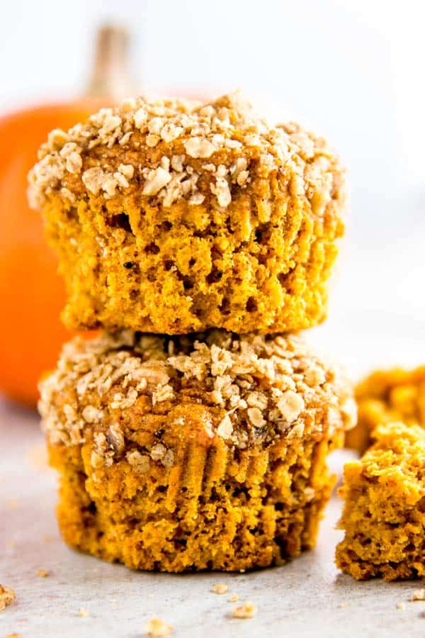 stack of healthy pumpkin muffins with a small orange pumpkin in the background