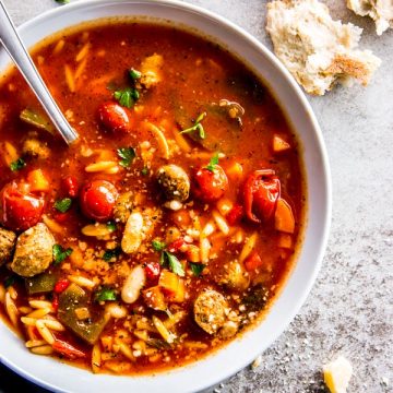 white soup plate filled with slow cooker tuscan white bean and sausage soup